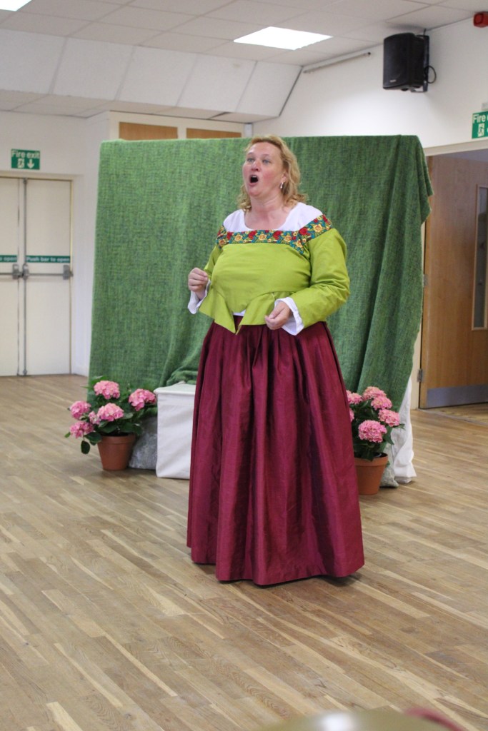 a woman in Tudor costume singing