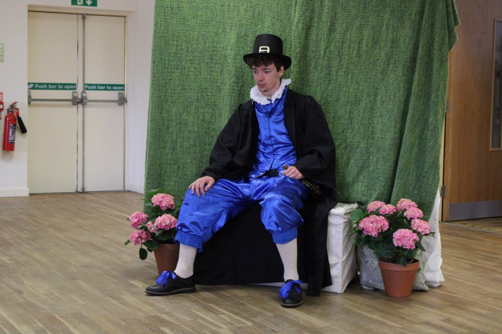 A man in Tudor costume sitting on a bench