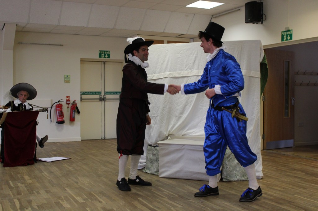 Two men in early modern costume shaking hands.