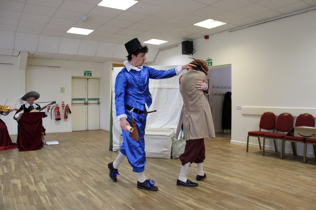 A man hugging himself is interrupted by another man