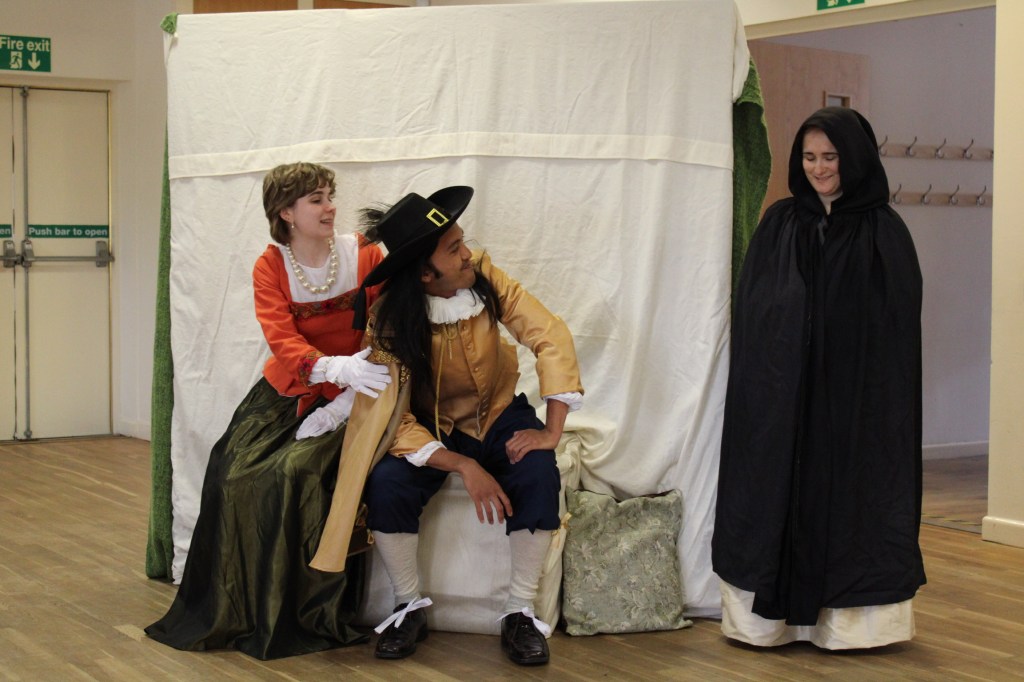 A woman holds a man, who is staring at another woman